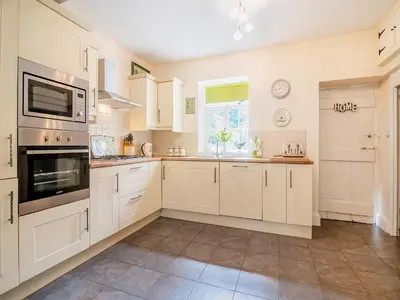 a large kitchen with white cabinets and a window at Court House in Hay-on-Wye