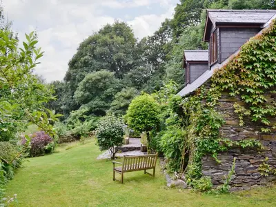 a bench sitting in the grass next to a building at Erw Goed Hen Feudy in Arthog