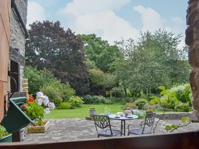 a patio with a table and chairs in a garden at The Bothy-E2934 in Clun