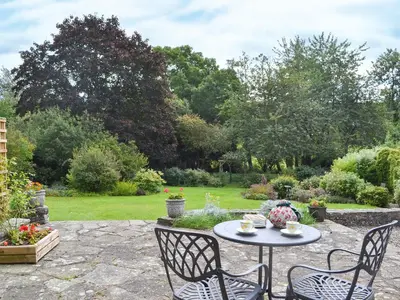 a patio with a table and chairs in a garden at The Bothy-E2934 in Clun