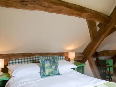 a bedroom with a white bed with wooden beams at The Bothy-E2934 in Clun