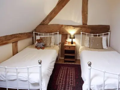 two beds in a attic bedroom with a teddy bear sitting between them at The Olde Granary - E4298 in Halston