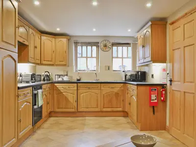 a large kitchen with wooden cabinets and appliances at The Olde Granary - E4298 in Halston