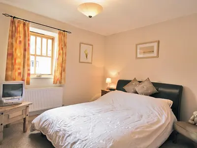 a bedroom with a bed and a tv and a window at Shippon Cottage - E4299A in Halston