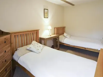 a bedroom with two beds and a dresser with a lamp at Shippon Cottage - E4299A in Halston