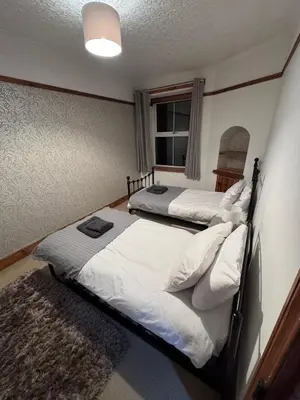 a bedroom with two beds and a window at Glannant - 5 Bed & 4 Bathroom - Fairbourne, Barmouth, Mawddach Estuary in Arthog