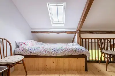 a bed in a room with two chairs and a window at Ashford Bridge Barn in Ludlow