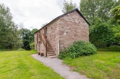 an old brick building with stairs in a field at Ashford Bridge Barn in Ludlow