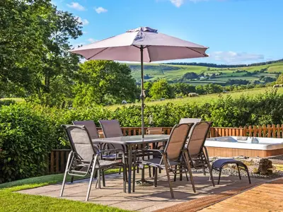 a table and chairs with an umbrella on a patio at Ash Lodge - Hw7442 in Nantmel