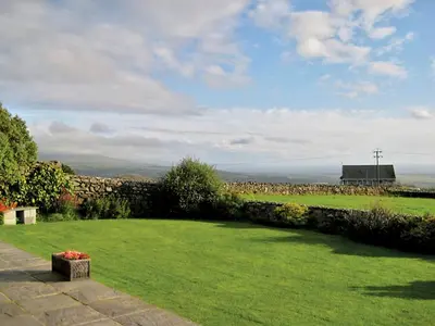 a garden with green grass and a stone wall at Rhiwgoch - Hw7449 in Harlech