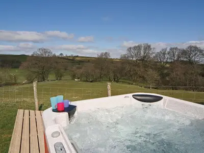 a jacuzzi tub with a bench and a field at Ithon Bank - Hw7478 in Penybont