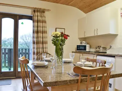 a kitchen and dining room with a table with flowers at Woodside Lodge - Hw7520 in Penybont