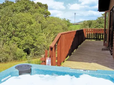 a hot tub on a house with a wooden deck at Woodside Lodge - Hw7520 in Penybont