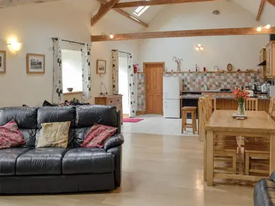 a living room and kitchen with a black leather couch at Dol Afon - Hw7588 in Llanuwchllyn