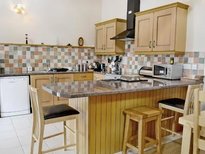 a kitchen with wooden cabinets and a counter with stools at Dol Afon - Hw7588 in Llanuwchllyn