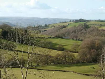 a view of a green field with trees and hills at Cwm Corn Barn - Hw7662 in Mochdre