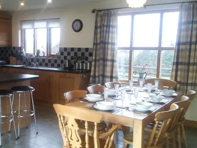 a kitchen with a wooden table with chairs around it at Cwm Corn Barn - Hw7662 in Mochdre