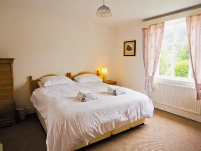 a bedroom with a bed with white sheets and a window at Station House - Hw7742 in Glyn-Dyfrdwy