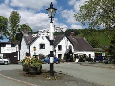 a street sign in front of a white building at The Coach House - Hw7782 in Llanarmon Dyffryn-Ceiriog