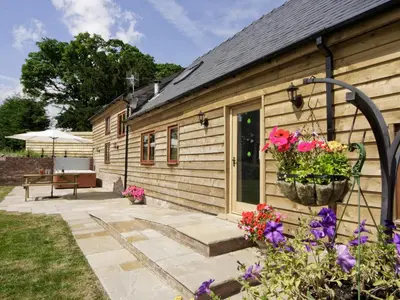 a wooden house with a patio and flowers at Cefnaire Isaf in Newtown