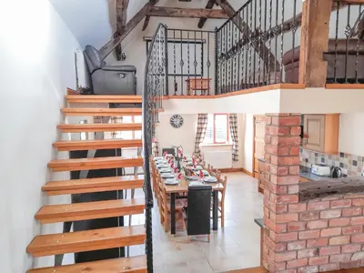 a room with a staircase and a table with chairs at Cefnaire Isaf in Newtown