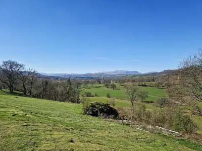 a green field with trees and hills in the background at Arenig - Uk48508 in Bala