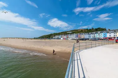 a person walking on the beach near the water at Fabulous Sea View Apartment in Aberdyfi