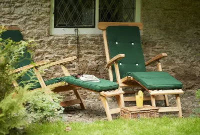 two green chairs sitting next to a house at Bull Hollow Cottage in Shrewsbury