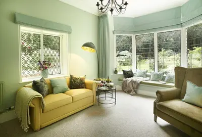 a living room with a yellow couch and windows at Bull Hollow Cottage in Shrewsbury