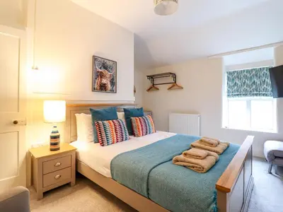 a bedroom with a large bed with a blue blanket at Golygfa'r Orsaf Snowdonia National Park in Bala