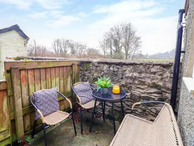a patio with a table and chairs and a fence at Golygfa'r Orsaf Snowdonia National Park in Bala