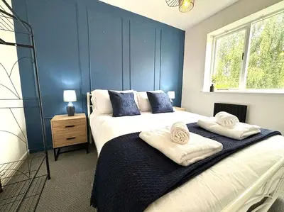 a bedroom with two beds and a blue wall at Shrewsbury Stayscape - Modern & Spacious 3BR - Family & Business Ready for 7 by Parydise Properties in Bicton