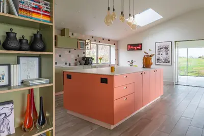 two images of a kitchen with an orange island at 1 Little Broomcroft in Shrewsbury