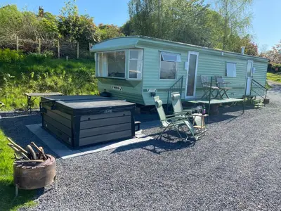 a green trailer with a table and a picnic table at Fabulous Hot Tub with Views! in Llanfair Caereinion