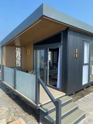a small black house with a porch and stairs at Lyons Sunnysands Caravan Park in Barmouth