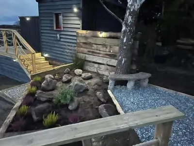 a garden with a tree and a wooden bench at Ty'r Bugail - Shepherds Hut in Llanddwywe