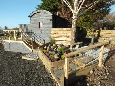 a garden with a wooden fence and a shed at Ty'r Bugail - Shepherds Hut in Llanddwywe