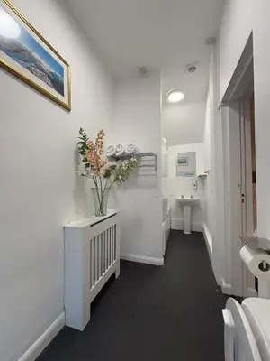 a white bathroom with a sink and a vase of flowers at Yak & Yeti in Shrewsbury