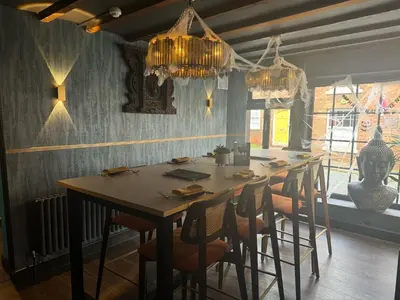 a dining room with a table with chairs and chandeliers at Yak & Yeti in Shrewsbury