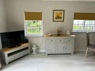 a living room with a television and two windows at Dog & Family Friendly Private Cottage in Orleton in Orleton