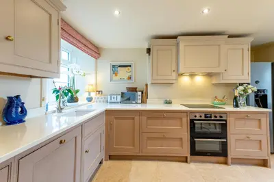 a kitchen with white cabinets and a sink at The Garden Cottage in Craven Arms
