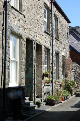 an old stone building with potted plants on it at Cysgod Idris Cottage in Dolgellau