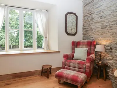 a living room with a chair and a mirror at Evenjobb Court Farmhouse in Presteigne