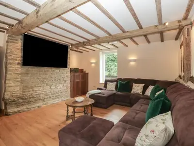 a living room with a couch and a tv at Evenjobb Court Farmhouse in Presteigne