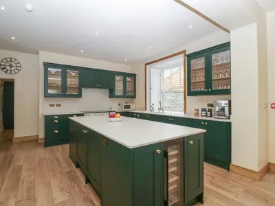 a kitchen with green cabinets and a white counter top at Evenjobb Court Farmhouse in Presteigne