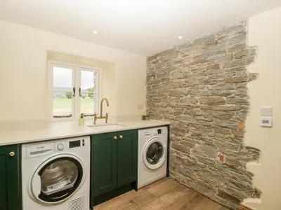 a stone wall in a laundry room with a washer and dryer at Evenjobb Court Farmhouse in Presteigne