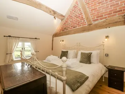 a bedroom with a bed and a brick wall at Evenjobb Court Farmhouse in Presteigne
