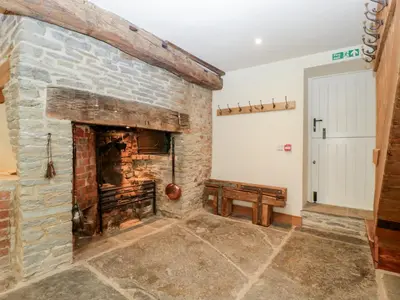 a stone fireplace in a living room with a bench at Evenjobb Court Farmhouse in Presteigne