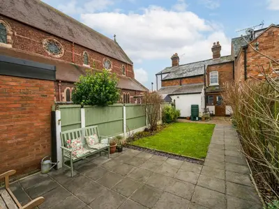 a garden with a bench in front of a building at Colourful homely 2 bed terrace - Pass the Keys in Shrewsbury