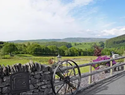 a stone fence with a stone wheel next to a stone wall at Golygfar Mynydd in Ystrad Meurig